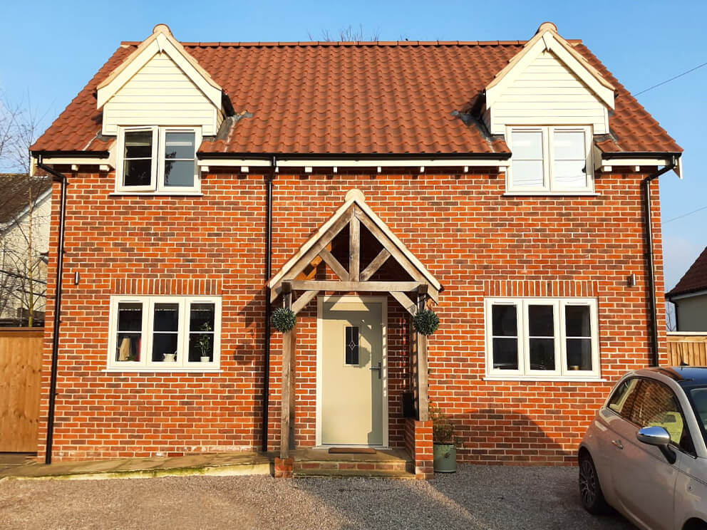 Completed red-brick new-build home with timber porch